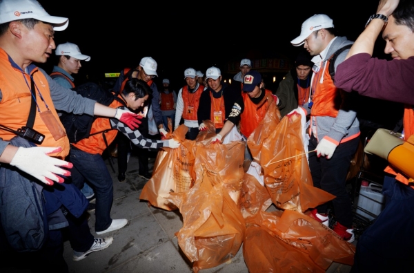700명의 한화 임직원을 포함한 시민자원봉사자 1400명이 밤늦게까지 쓰레기를 수거하며 클린캠페인(환경정화활동)을 펼치는 모습이다