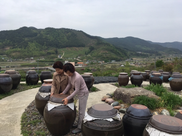 마을 어르신의 방문에 발효중인 장독을 열여 보여준다.
